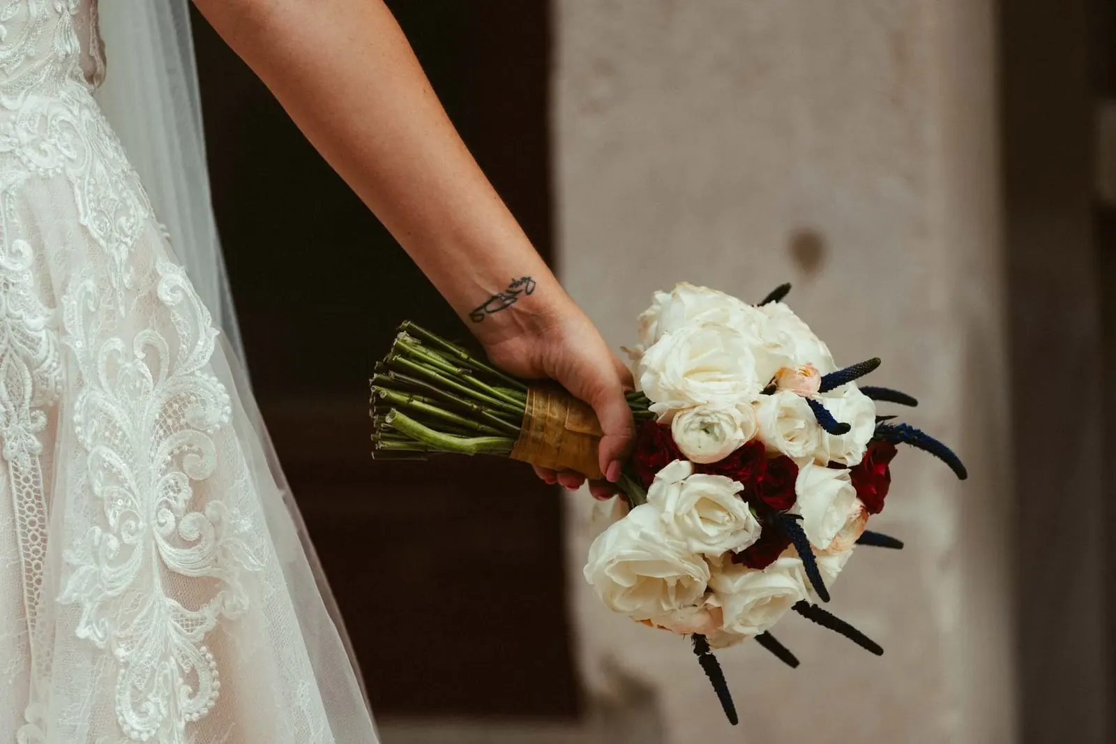 A bride's lace sleeve and white rose bouquet