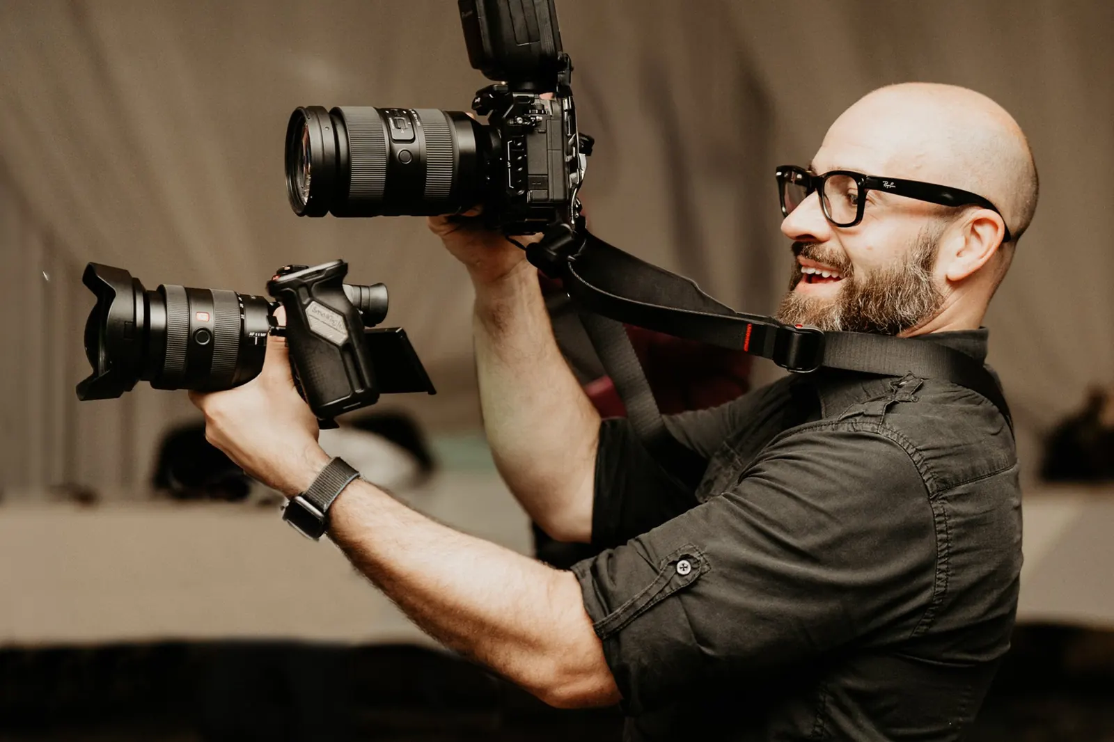 Dan laughing behind a camera with two lenses mounted