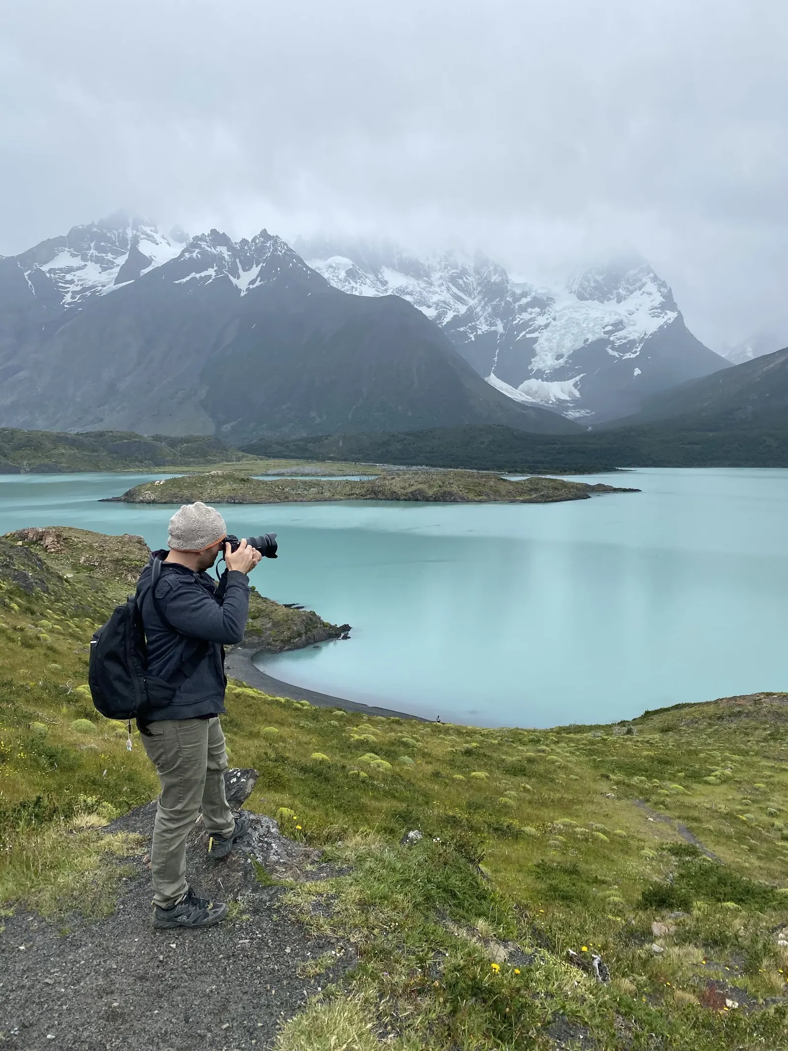 Dan photographing a turquoise mountain lake beneath snowy peaks