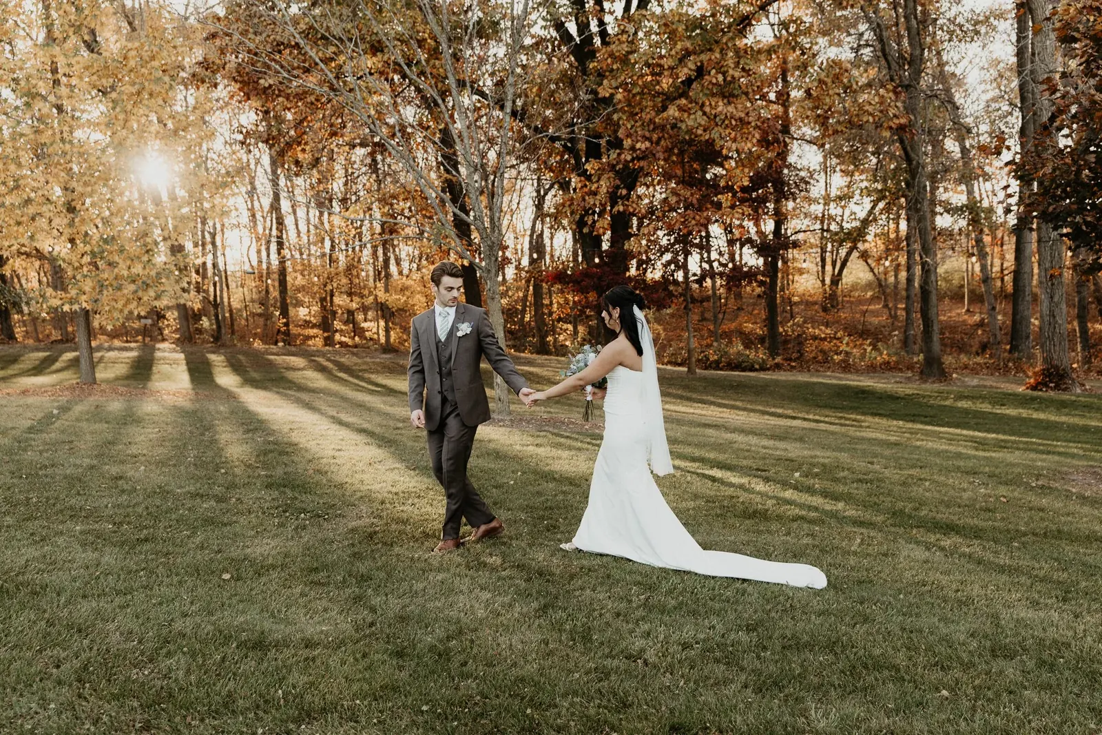 A couple walking through autumn trees at sunset