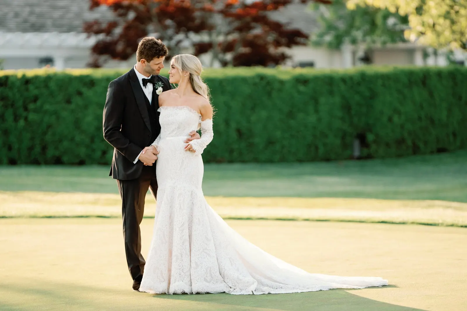 A couple embracing on an estate lawn at golden hour
